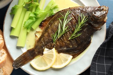Photo of Tasty roasted flounder fish with celery served on blue table, closeup. Homemade seafood dish
