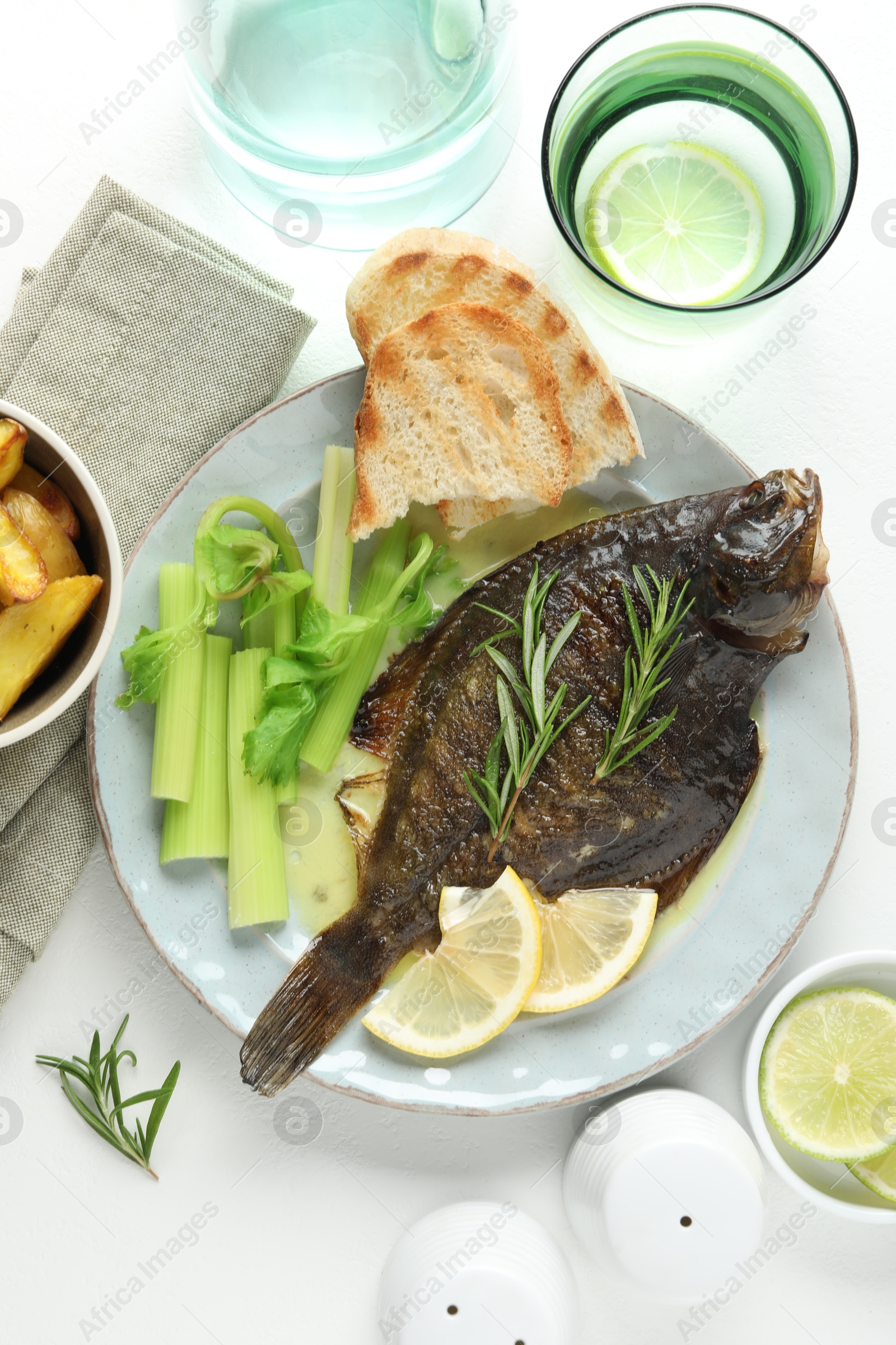 Photo of Tasty roasted flounder fish with celery served on white table, flat lay. Homemade seafood dish
