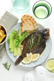 Photo of Tasty roasted flounder fish with celery served on white table, flat lay. Homemade seafood dish