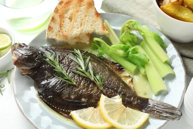 Photo of Tasty roasted flounder fish with celery served on white table, closeup. Homemade seafood dish