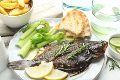 Photo of Tasty roasted flounder fish with celery served on white table, closeup. Homemade seafood dish