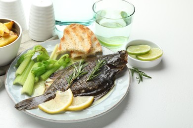 Photo of Tasty roasted flounder fish with celery served on white table, closeup. Homemade seafood dish