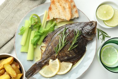 Photo of Tasty roasted flounder fish with celery served on white table, flat lay. Homemade seafood dish