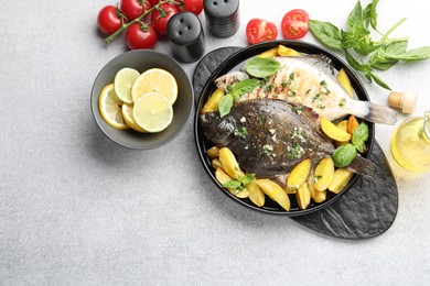 Photo of Tasty roasted flounder fish with herbs, potato, lemon slices and tomatoes on light table, flat lay. Homemade seafood dish