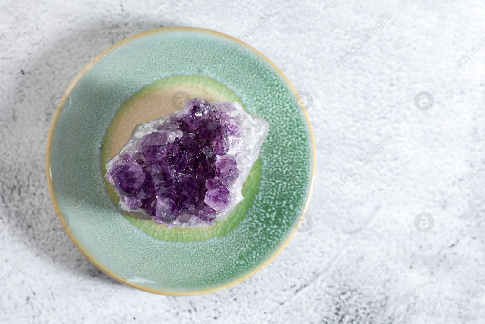 Photo of Aura. Beautiful amethyst on white textured table, top view. Space for text