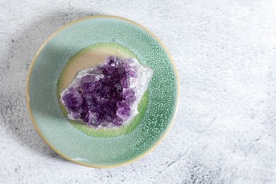 Photo of Aura. Beautiful amethyst on white textured table, top view. Space for text