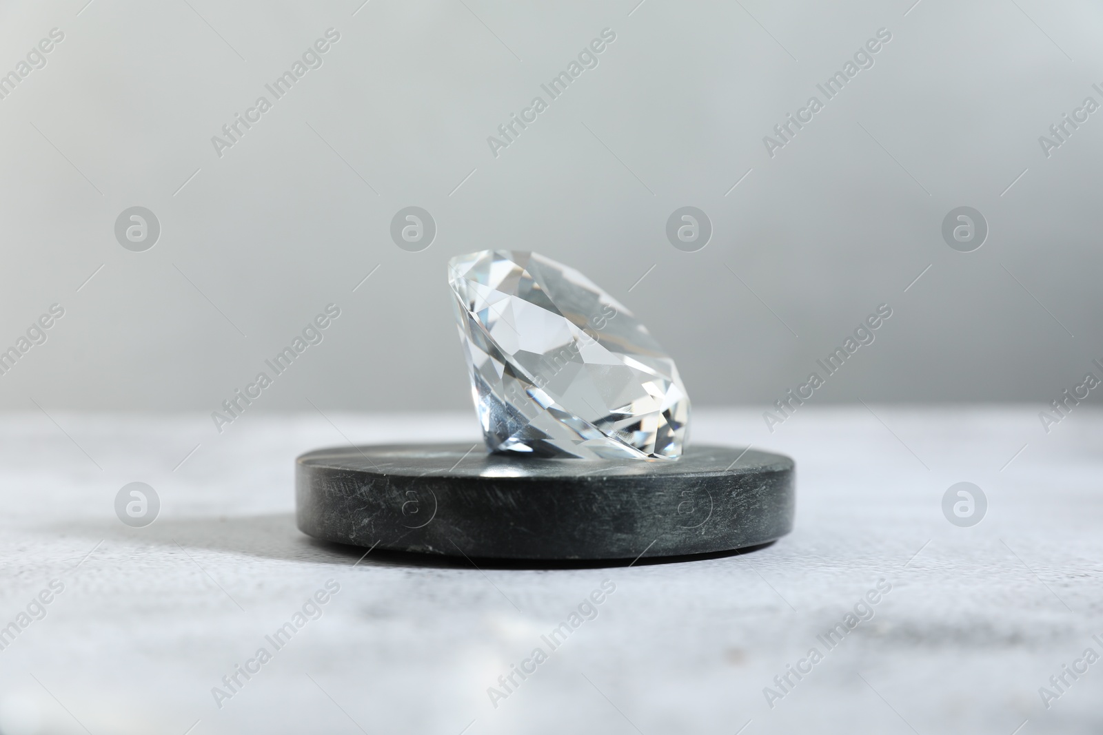 Photo of Aura. Beautiful diamond on white textured table, closeup