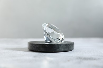 Photo of Aura. Beautiful diamond on white textured table, closeup