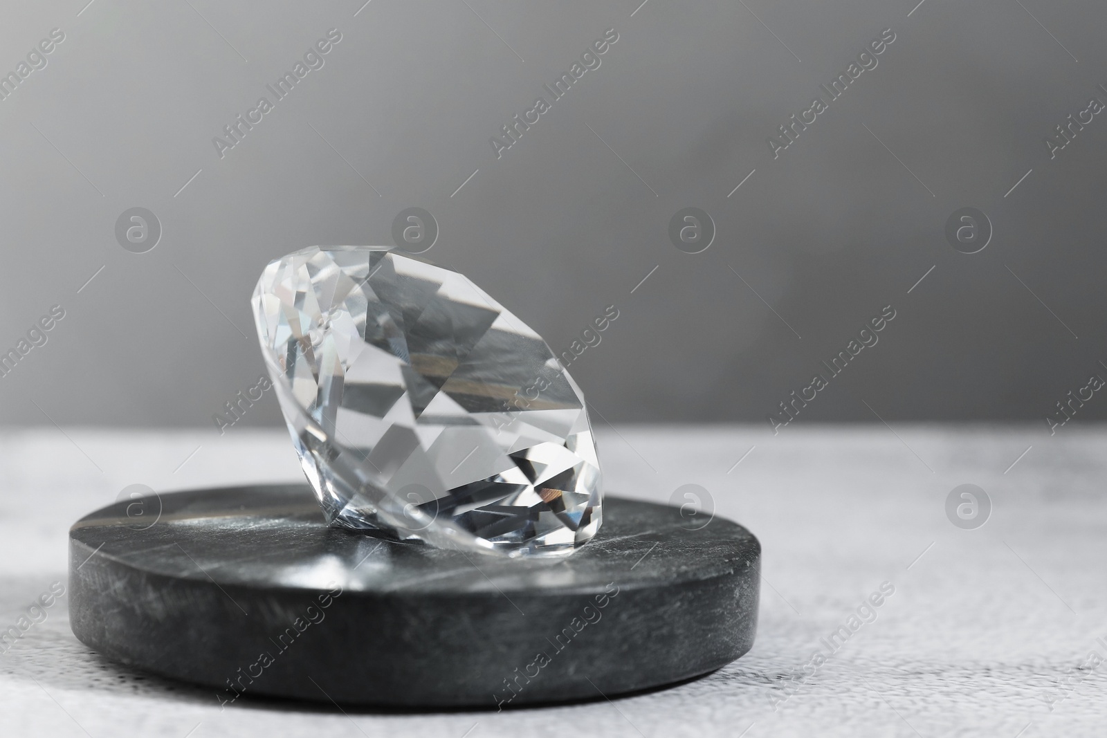 Photo of Aura. Beautiful diamond on white textured table, closeup. Space for text