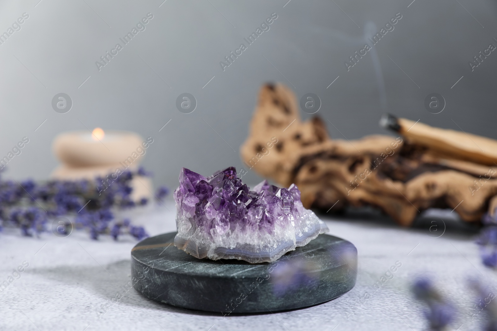 Photo of Aura. Beautiful amethyst, lavender, burning candle and Palo Santo stick on white textured table, closeup