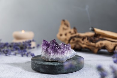 Photo of Aura. Beautiful amethyst, lavender, burning candle and Palo Santo stick on white textured table, closeup
