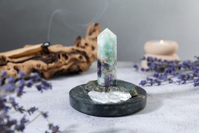 Photo of Aura. Different crystals, lavender, burning candle and Palo Santo on white textured table, closeup