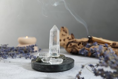 Photo of Aura. Different crystals, lavender, burning candle and Palo Santo on white textured table