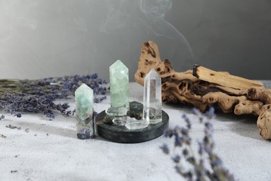 Photo of Aura. Different crystals, lavender and Palo Santo stick on white textured table
