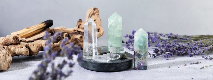 Photo of Aura. Different crystals, lavender and Palo Santo stick on white textured table