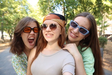 Photo of Happy friends in sunglasses taking selfie outdoors