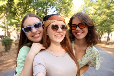 Photo of Happy friends in sunglasses taking selfie outdoors
