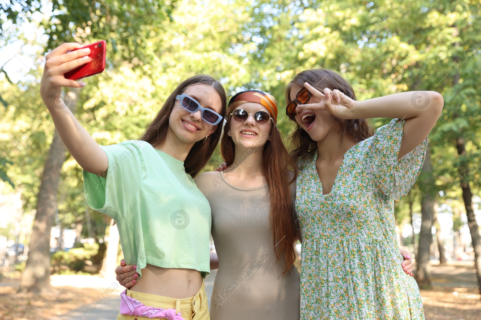 Happy friends in sunglasses taking selfie outdoors Photo of Happy friends in sunglasses taking selfie outdoors