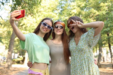 Photo of Happy friends in sunglasses taking selfie outdoors