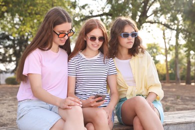 Photo of Friends with smartphone on bench in park