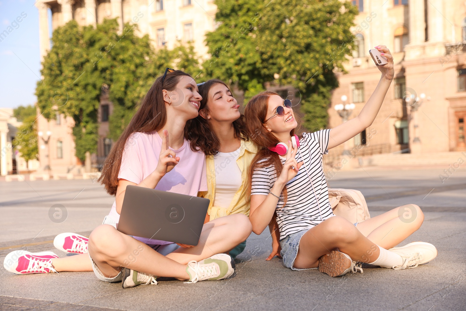 Happy friends taking selfie with smartphone on asphalt outdoors Photo of Happy friends taking selfie with smartphone on asphalt outdoors