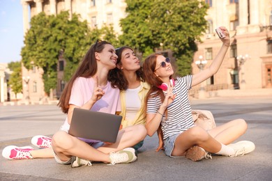 Photo of Happy friends taking selfie with smartphone on asphalt outdoors