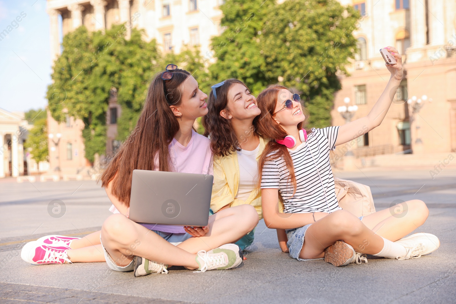 Photo of Happy friends taking selfie with smartphone on asphalt outdoors