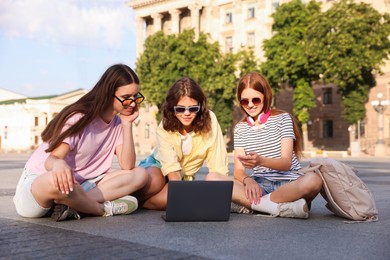 Photo of Three friends watching something on laptop outdoors
