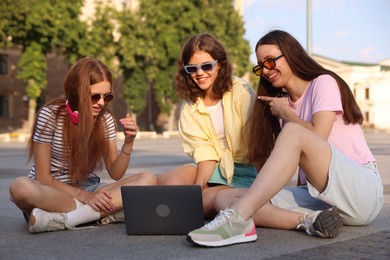 Photo of Three friends watching something on laptop outdoors