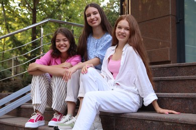 Photo of Three happy friends sitting on stairs outdoors