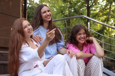 Photo of Three happy friends sitting on stairs outdoors