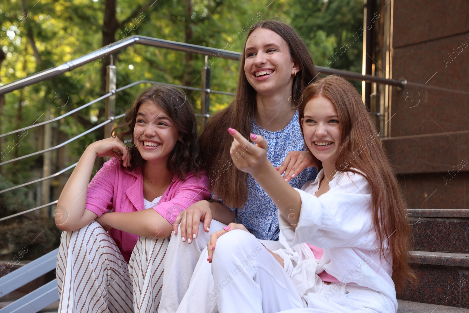 Photo of Three happy friends sitting on stairs outdoors