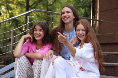 Photo of Three happy friends sitting on stairs outdoors