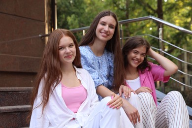 Photo of Three happy friends sitting on stairs outdoors