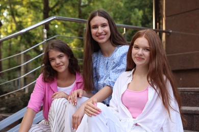 Photo of Three happy friends sitting on stairs outdoors