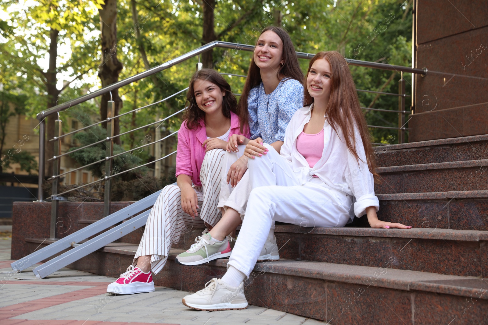 Photo of Three happy friends sitting on stairs outdoors