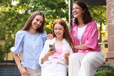 Photo of Happy friends with smartphone on city street