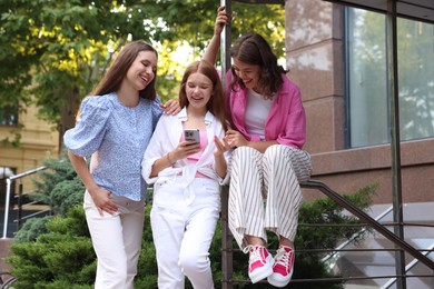 Photo of Happy friends with smartphone on city street