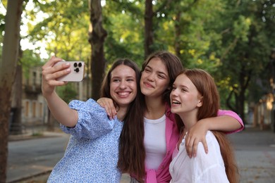 Photo of Happy friends taking selfie with smartphone in park