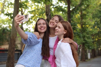 Photo of Happy friends taking selfie with smartphone in park