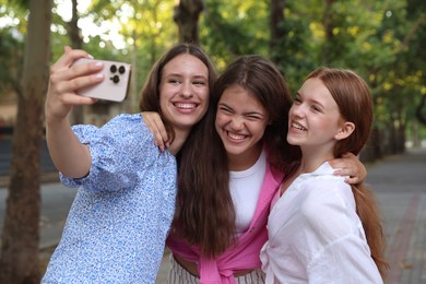 Photo of Happy friends taking selfie with smartphone in park