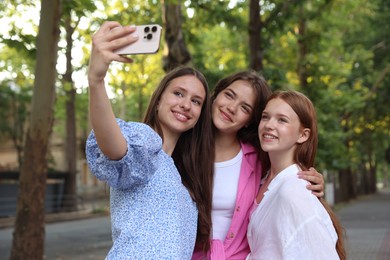 Photo of Happy friends taking selfie with smartphone in park