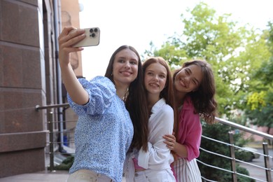 Photo of Happy friends taking selfie on city street