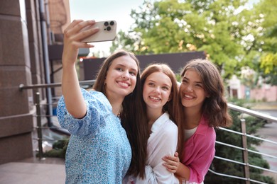 Photo of Happy friends taking selfie on city street