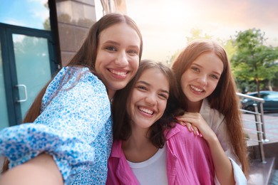 Photo of Happy friends taking selfie on city street