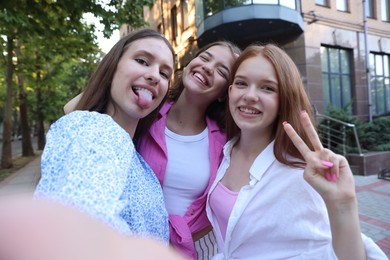 Photo of Happy friends taking selfie on city street