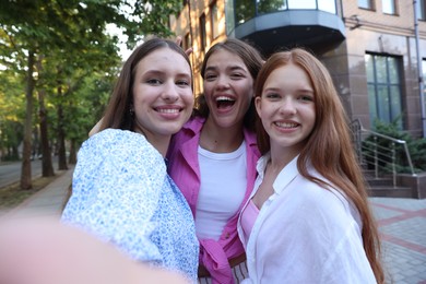 Photo of Happy friends taking selfie on city street