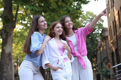 Photo of Happy friends walking together on city street, low angle view