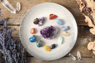 Photo of Aura. Different natural mineral stones, lavender and snag on wooden table, flat lay