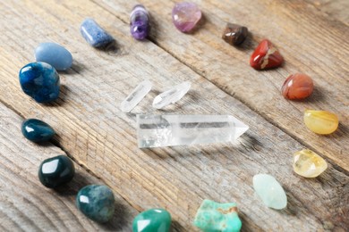 Photo of Aura. Different natural mineral stones on wooden table, closeup